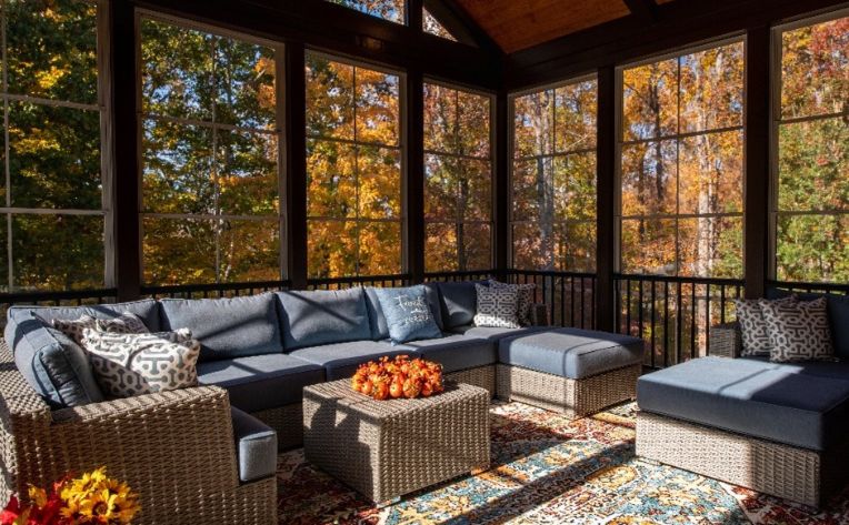 A sunroom with patio sofa set in grey with blue cushions